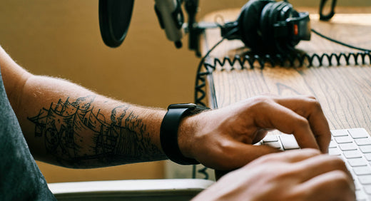 Hands typing on keyboard with headphones in background