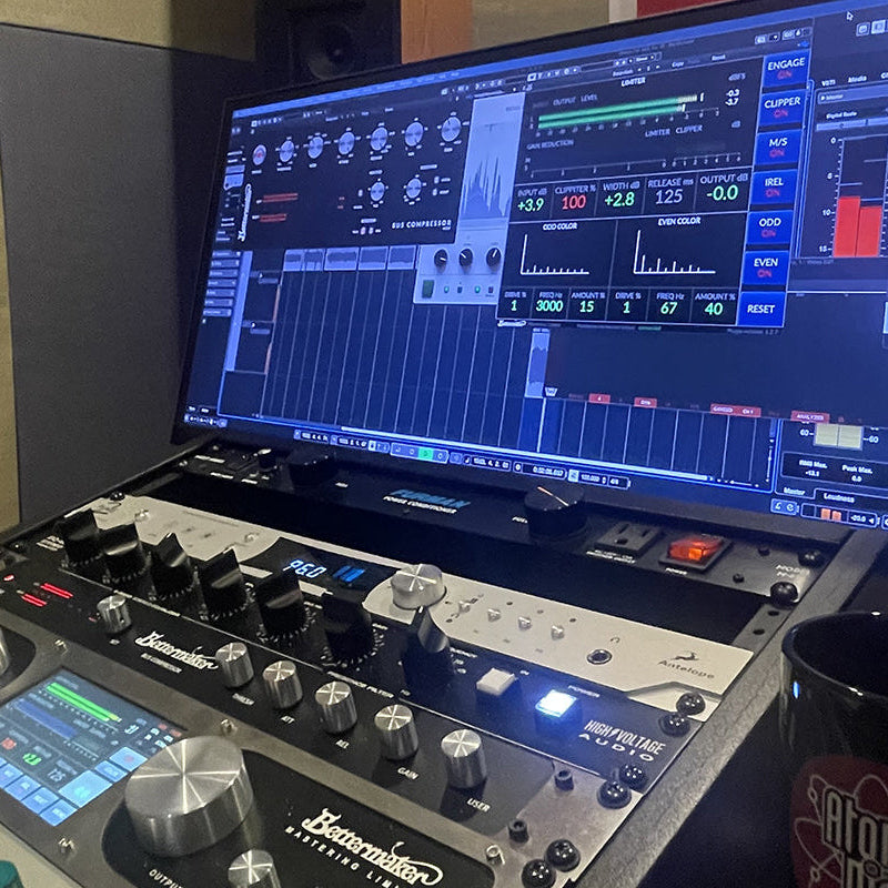 Music production setup with mixing console and computer screen in a studio.